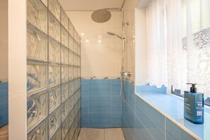 Ein Badezimmer mit Dusche, Waschbecken und einer Shampooflasche auf der Ablagefläche.