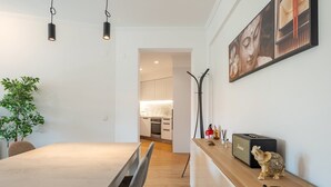 Un interior moderno con zona de comedor, cocina y estante decorativo con figuritas.