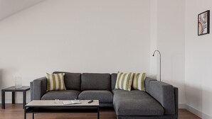 Una sala de estar moderna con un sofá seccional gris, una mesita auxiliar y una lámpara de pie.