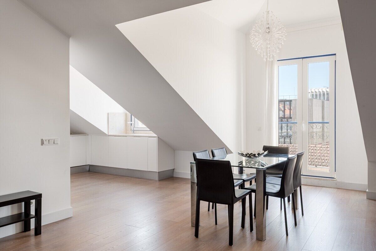 Zona pranzo moderna con tavolo e sedie in vetro, lampadario a sospensione e vista sulla città attraverso un'ampia finestra.