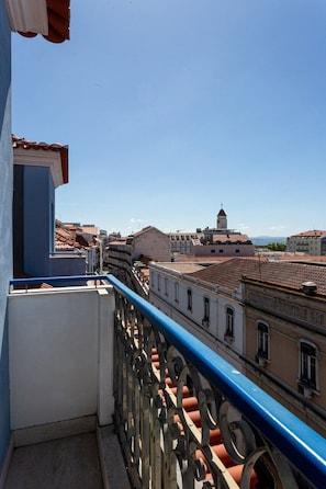 A balcony with a blue railing overlooking a cityscape with historical buildings and a tower. - GuestReady - Gorgeous apt with river view (Lisbon)