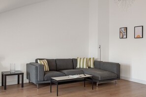 A modern living room with a grey sectional sofa, a small side table, and a coffee table. - GuestReady - Gorgeous apt with river view (Lisbon)