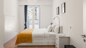 Un dormitorio con cama, mesita de noche y vistas al exterior.