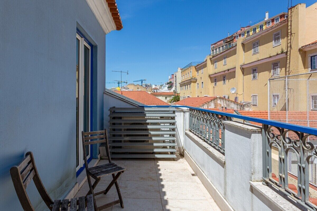 Un balcone con vista sulla città, un cancello in metallo e una panca di legno.
