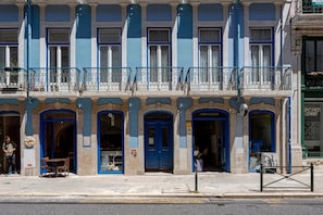 A building with multiple ground-floor shops, including a laundry and a boutique. - GuestReady - Gorgeous apt with river view (Lisbon)