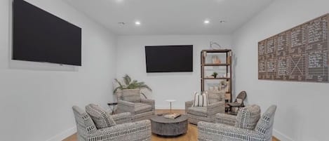 Ein modernes Wohnzimmer mit Korbmöbeln, einem Flachbildfernseher und einer dekorativen Wandkarte.