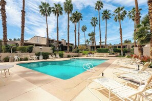 A swimming pool with lounge chairs and palm trees. - Noline Hideaway by GPM - Chic 2BR Condo Ironwood CC, Palm Desert (Palm Desert)