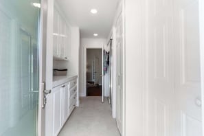 A narrow hallway with white doors, a marble countertop, and a small bench. - Noline Hideaway by GPM - Chic 2BR Condo Ironwood CC, Palm Desert (Palm Desert)