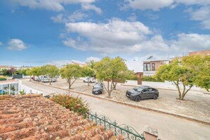 Een woonstraat met geparkeerde auto's, bomen en huizen.