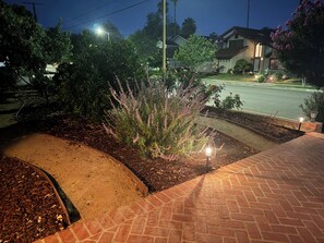 A landscaped garden area with a paved walkway, a variety of plants, and a street in the background. - Spacious 4-bedroom house with pool in perfect Los Angeles neighborhood (Los Angeles)