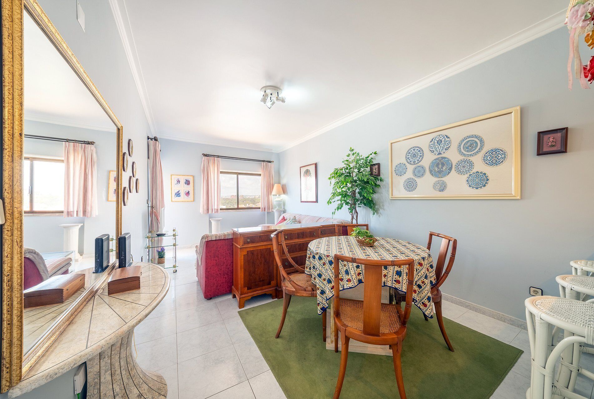 A dining area with a round table, chairs, and a green rug.
