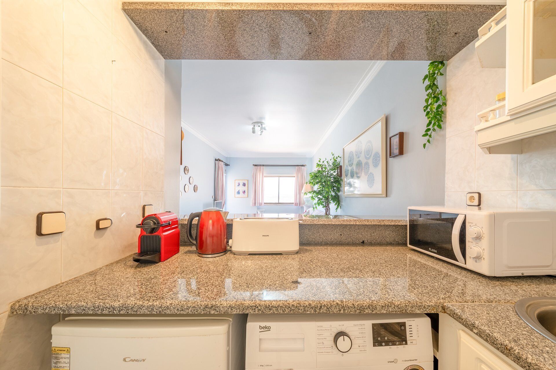 Una cocina con encimeras de granito, cafetera, microondas y lavavajillas.