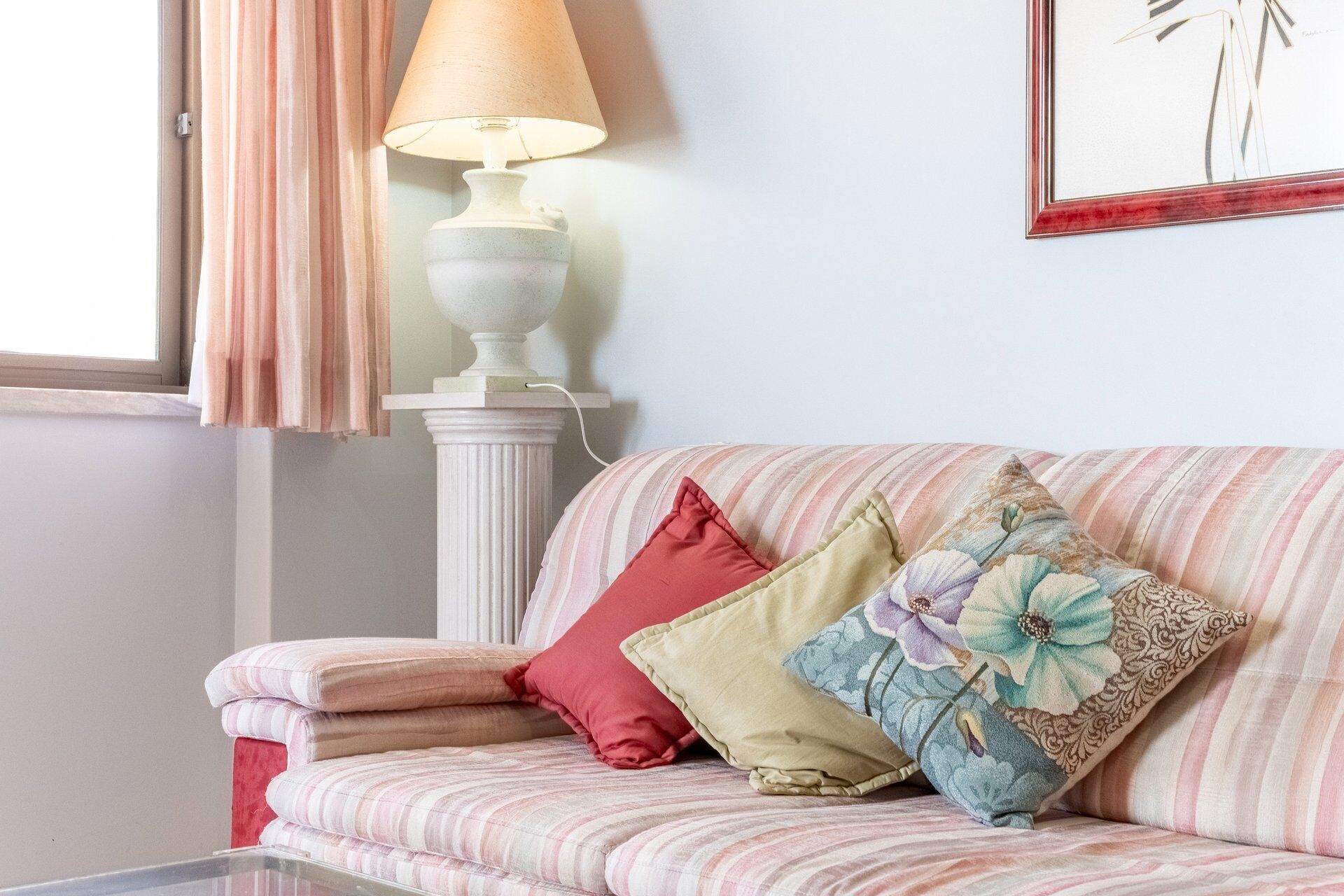 Quarto com sofá listrado, luminária e quadro pendurado na parede.