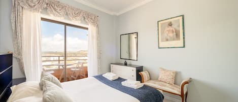 A bedroom with a bed, a chair, a dresser, a mirror, and a framed picture on the wall.
