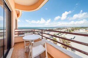 Ein Balkon mit Tisch und Stühlen mit Blick auf Strand und Stadtlandschaft.