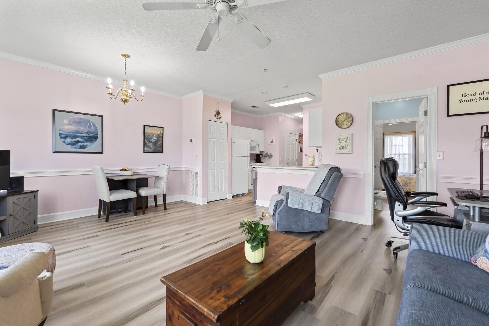A modern living room with a dining area, kitchen, and a ceiling fan.