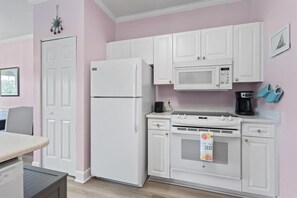 A kitchen with white cabinets, a refrigerator, a microwave, a stove, and a coffee maker. - King Bed 1BR Condo | Golf View | Pool (Myrtle Beach)