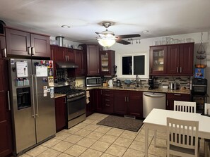 A modern kitchen with stainless steel appliances, dark wood cabinets, a granite countertop, and a ceiling fan. - 3-bedroom house close to EAA with AC and large FENCED back yard. (Oshkosh)