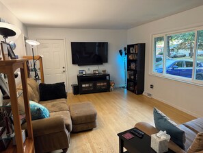 A living room with a sofa, a coffee table, a TV, and a bookshelf. - 3-bedroom house close to EAA with AC and large FENCED back yard. (Oshkosh)