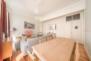 Een ruime woonkamer met een eettafel, banken en een televisie.