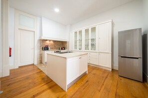 A modern kitchen with white cabinetry, a stainless steel refrigerator, and a wooden floor. - GuestReady - Family home near Santa Justa Lift (Lisbon)