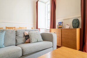 Un saló amb un sofà, una taula auxiliar de fusta i un moble amb objectes decoratius.