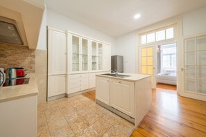 A modern kitchen with white cabinetry, a built-in oven, and a stainless steel refrigerator. - GuestReady - Family home near Santa Justa Lift (Lisbon)
