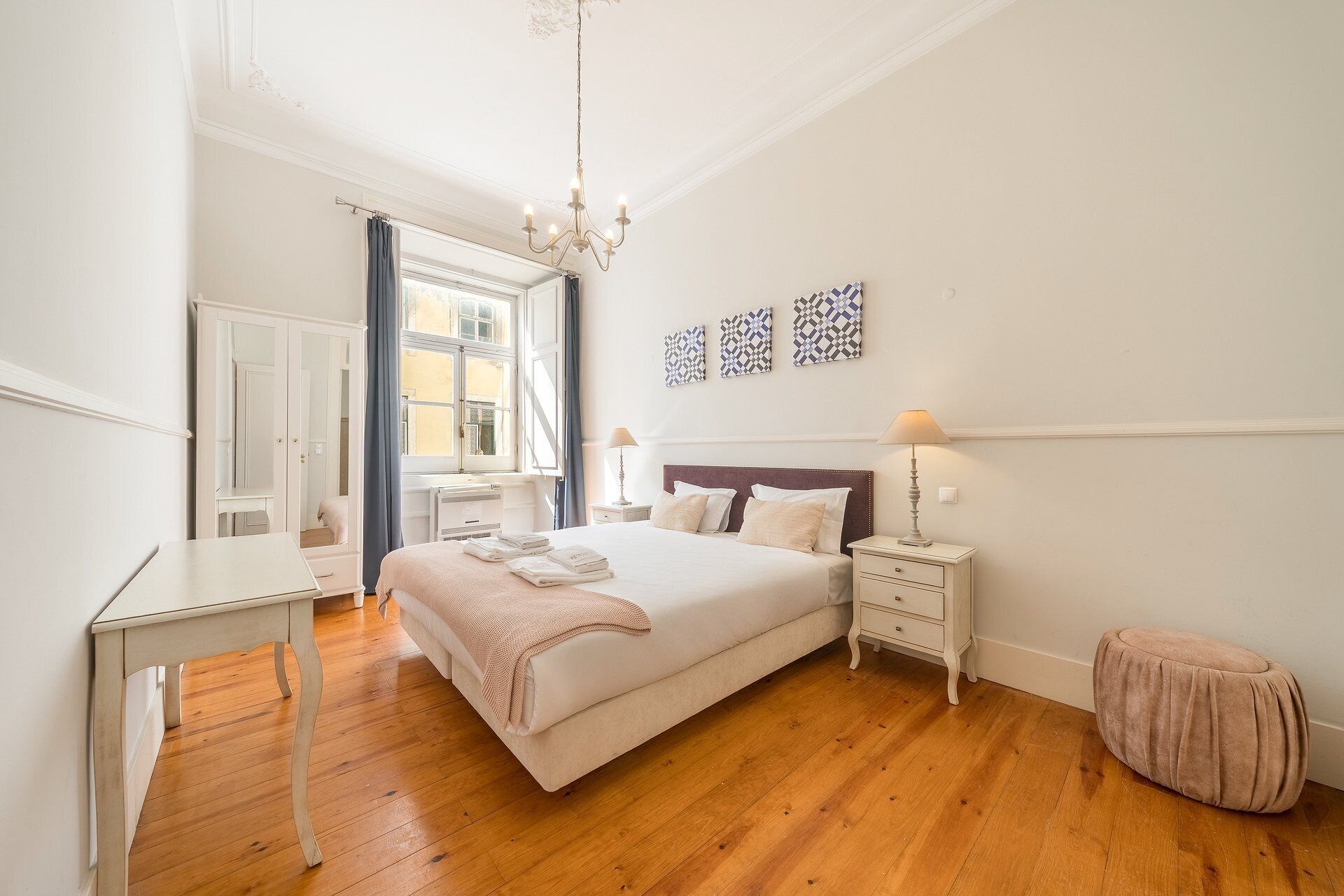Un dormitorio con cama, mesitas de noche, cómoda, espejo y candelabro.
