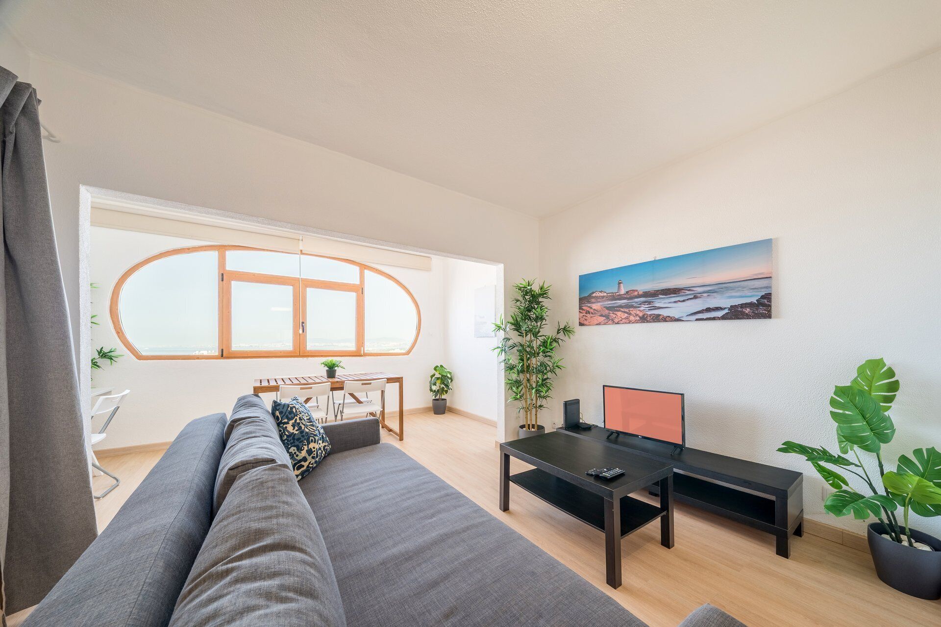A modern living room with a sofa, a dining table, and a TV.