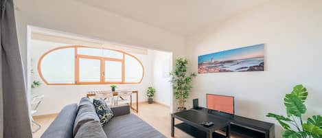 A modern living room with a sofa, a dining table, and a TV.