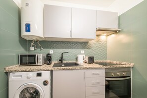 Eine kleine Küchenzeile mit Mikrowelle, Kaffeemaschine, Toaster und Waschmaschine.