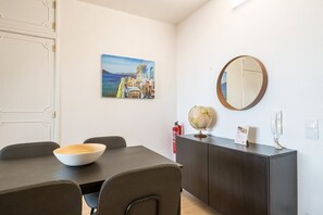 Ein Essbereich mit Tisch, Stühlen, einem Globus, einem Feuerlöscher und einem Gemälde an der Wand.