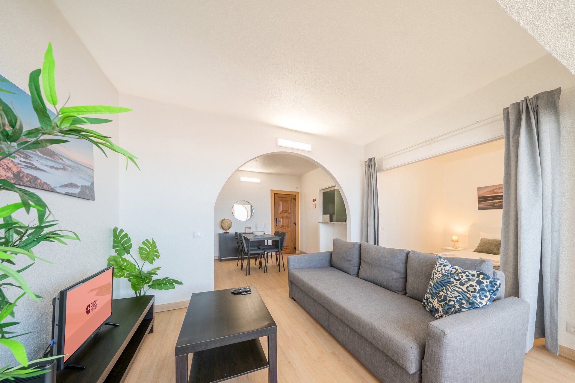 Een woonkamer met een bank, een salontafel en een televisie. Op de achtergrond een eethoek met een tafel en stoelen.