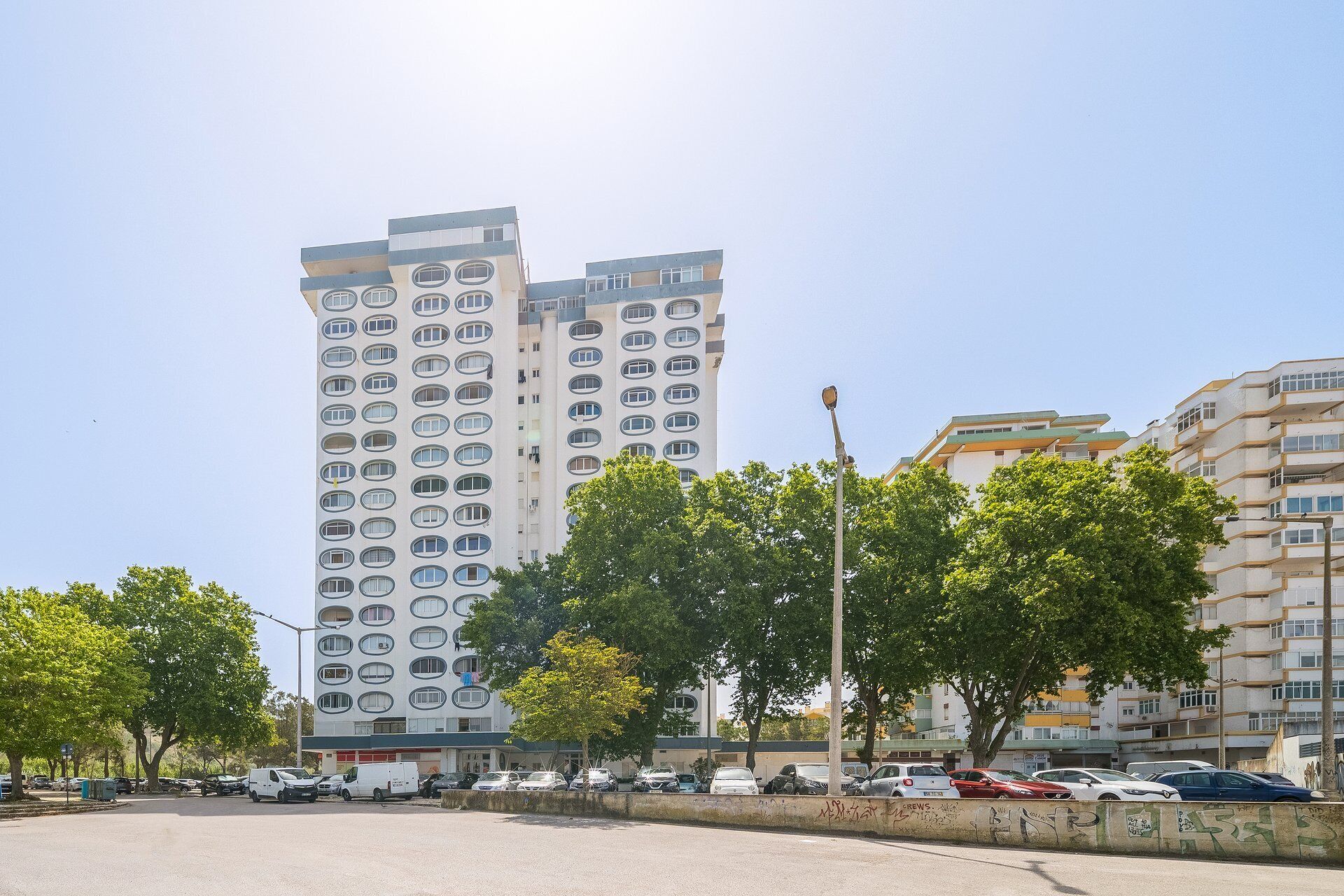 Ein mehrstöckiges Wohngebäude im modernen Architekturstil, mit mehreren Balkonen und einem Parkplatz im Vordergrund.