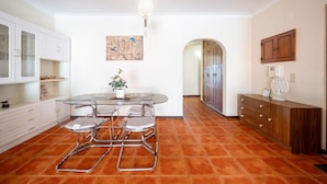Una cocina moderna con armarios blancos, una mesa de comedor de vidrio y una planta en maceta.
