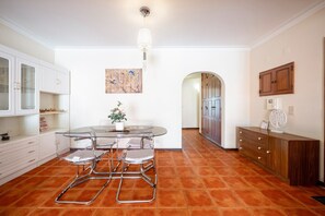 Una cocina moderna con armarios blancos, una mesa de comedor de vidrio y una planta en maceta.