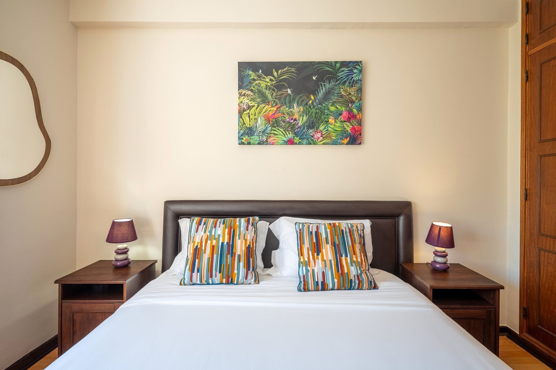 Ein Hotelzimmer mit einem Bett, zwei Nachttischen, einem Wandbild und einer Holztür.