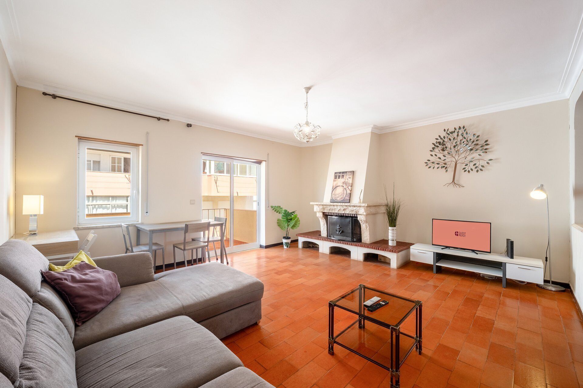 Een woonkamer met een bank, een salontafel, een open haard, een televisie en een eethoek met een tafel en stoelen.