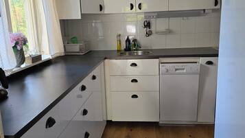 A kitchen with white cabinets, a dishwasher, and a window with curtains.