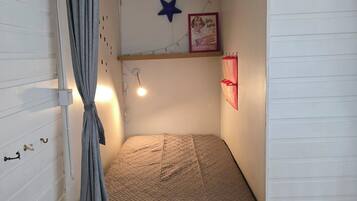 A small, single-bed room with a slanted ceiling, a star decoration, a framed picture, and a curtain.