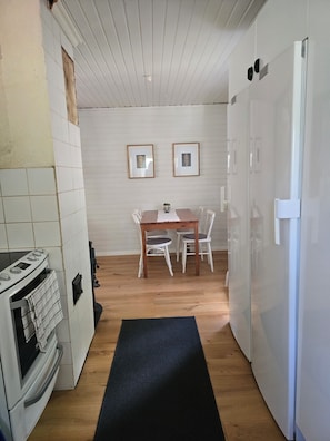 A compact kitchen with a dining area, a refrigerator, and a stove.