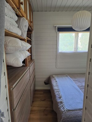 A bedroom with a bed, a wooden dresser, and a window.