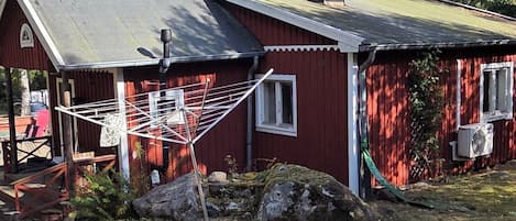 Une maison en bois rouge avec un étendoir métallique et un petit porche.