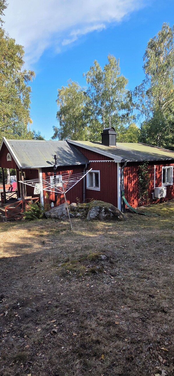 A red wooden house with a metal drying rack and a small porch.