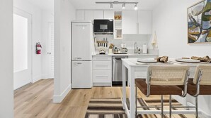 A modern kitchen with white cabinetry, a built-in oven, and a dining area with a table and chairs. - The Big Yellow House Loft C (Summerland)