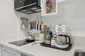 Una cuina amb una cafetera, un búl i una forta de cafè al taulell.