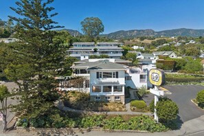 A multi-story residential building with a parking area and a sign indicating a golf course nearby. - The Big Yellow House Loft C (Summerland)