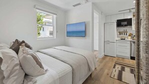 A bedroom with a bed, a window, and a view of the sea. - The Big Yellow House Loft C (Summerland)
