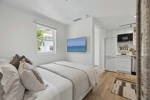 A bedroom with a bed, a window, and a view of the sea. - The Big Yellow House Loft C (Summerland)