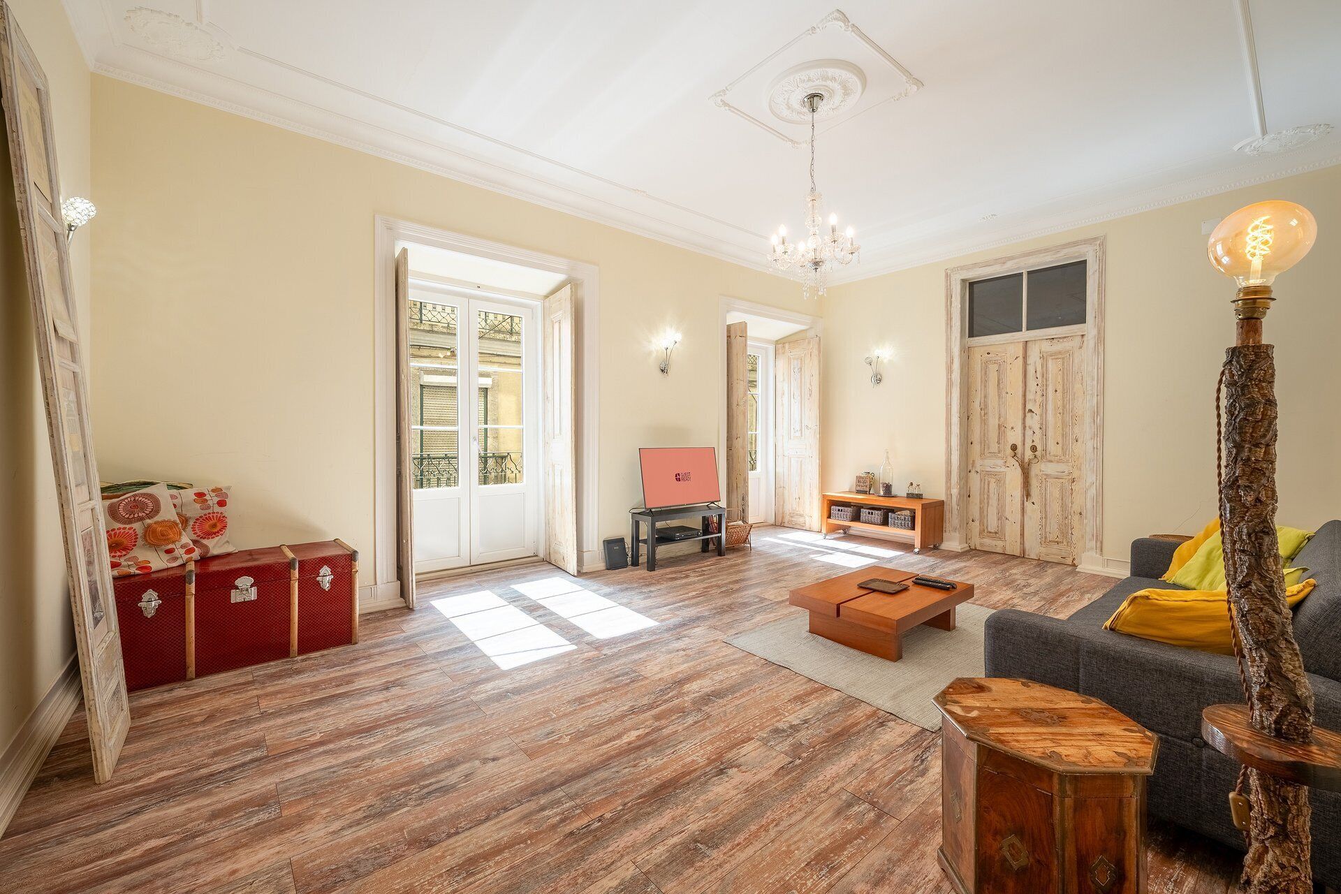Un salón espacioso con piso de madera, un sofá, una mesita de centro y una lámpara decorativa.